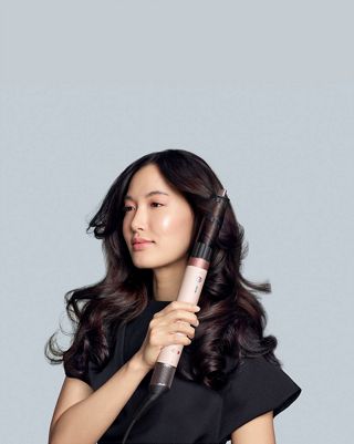 Створення об'ємних локонів на темному волоссі за допомогою стайлера Dyson Airwrap Ceramic Pink.