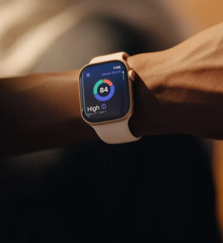 Смарт-годинник Apple Watch у світлому корпусі на зап'ясті користувача. На дисплеї відкрито додаток для відстеження сну, який демонструє високу загальну оцінку якості відпочинку (Sleep Score 84) у вигляді кольорового графіка