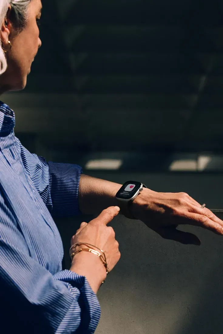 Сповіщення про стан здоров'я серця на екрані Apple Watch на зап'ясті користувачки