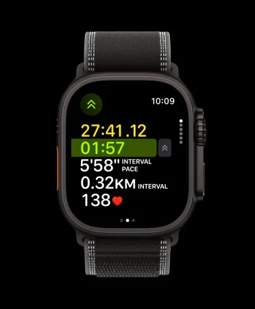 Смарт-годинник Apple Watch Ultra 3 у чорному титановому корпусі з темним ремінцем Trail Loop на чорному тлі. На екрані продемонстровано інтерфейс активного інтервального тренування: загальний час, час поточного інтервалу на зеленому фоні, темп інтервалу, дистанція інтервалу та пульс