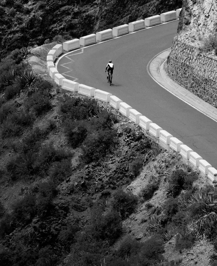 Чорно-біле фото велосипедиста на гірській дорозі, що підкреслює можливості Apple Watch Ultra 3 для велоспорту