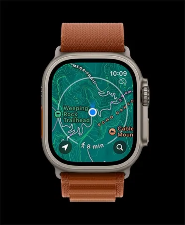 Смарт-годинник Apple Watch Ultra 3 у класичному титановому корпусі з помаранчевим текстильним ремінцем Alpine Loop на чорному тлі. На яскравому екрані відкрито детальну топографічну карту місцевості з лініями висот, відображенням поточної геолокації, навколишніми стежками та розрахунком часу в дороз