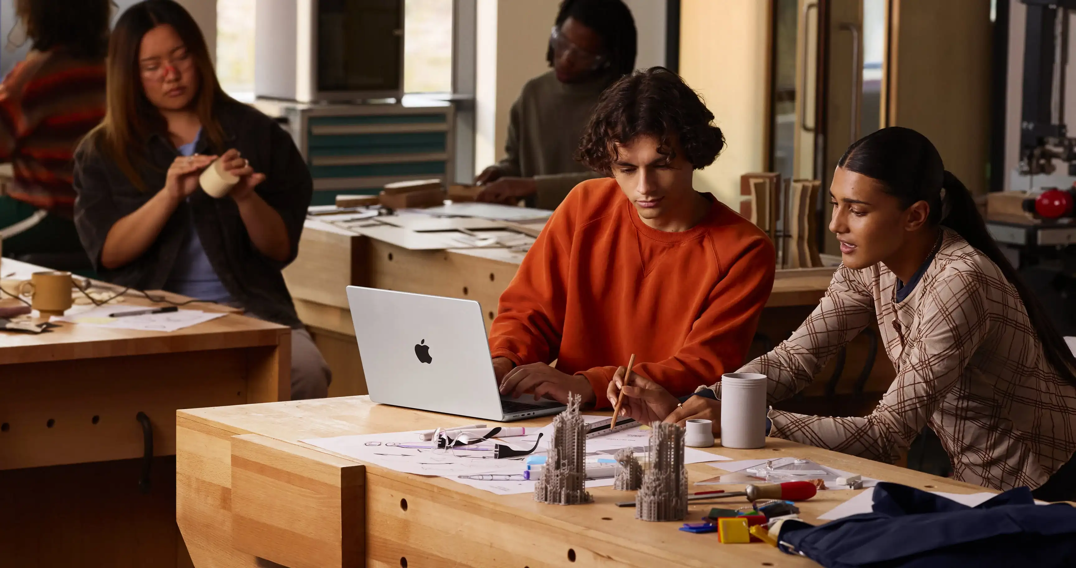 Студенти працюють над архітектурним макетом за ноутбуком MacBook Pro 14 M5 у майстерні