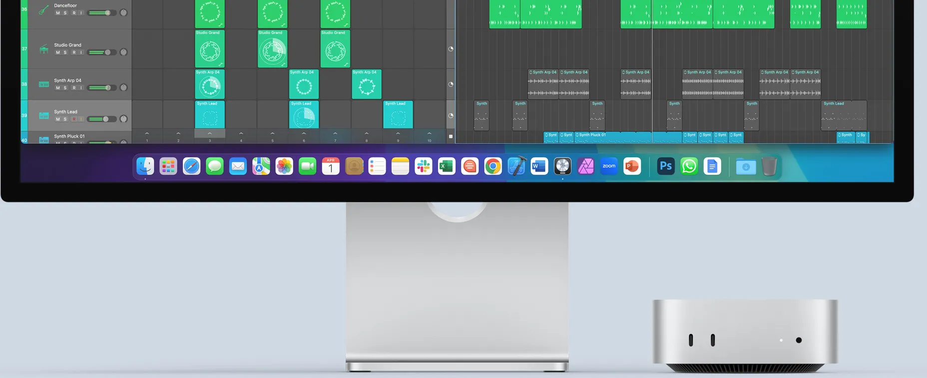 Вид спереду на сріблястий Mac mini, на передній панелі якого показано порти та світлодіодний індикатор. Він розташований під монітором Mac, на екрані якого відображається кольорове зображення й іконки додатків на панелі Dock