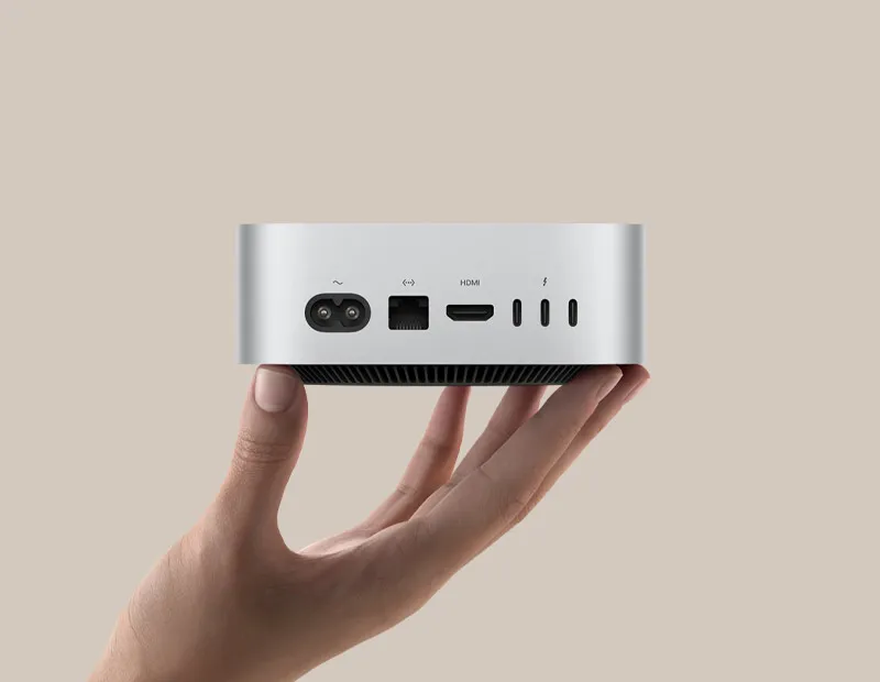 Користувач тримає Mac mini, демонструючи його порти на задній панелі