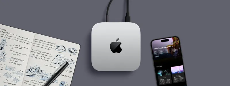 Вид зверху на сріблястий Mac mini з логотипом Apple. Поруч із ним на столі лежать iPhone, ручка та відкритий записник із рукописними нотатками